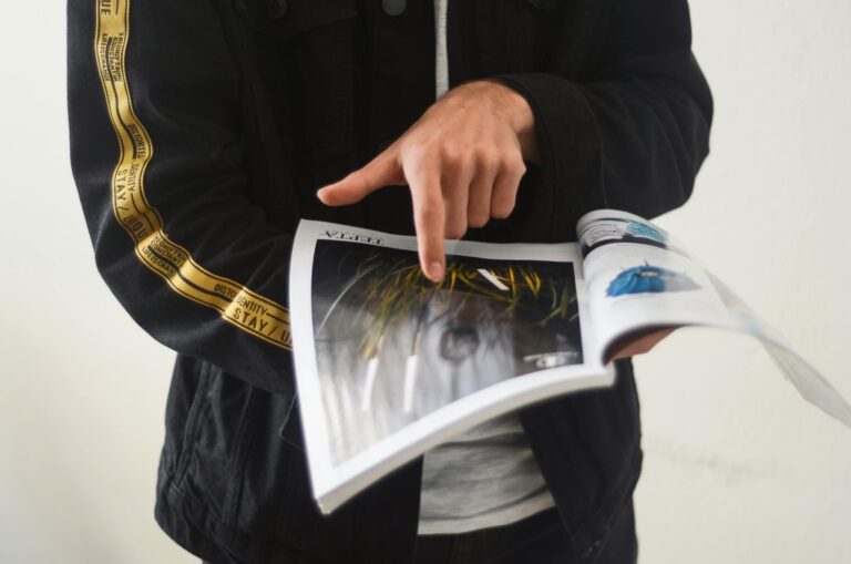 Close-up of a person pointing at a page in an open magazine. Ideal for editorial content.