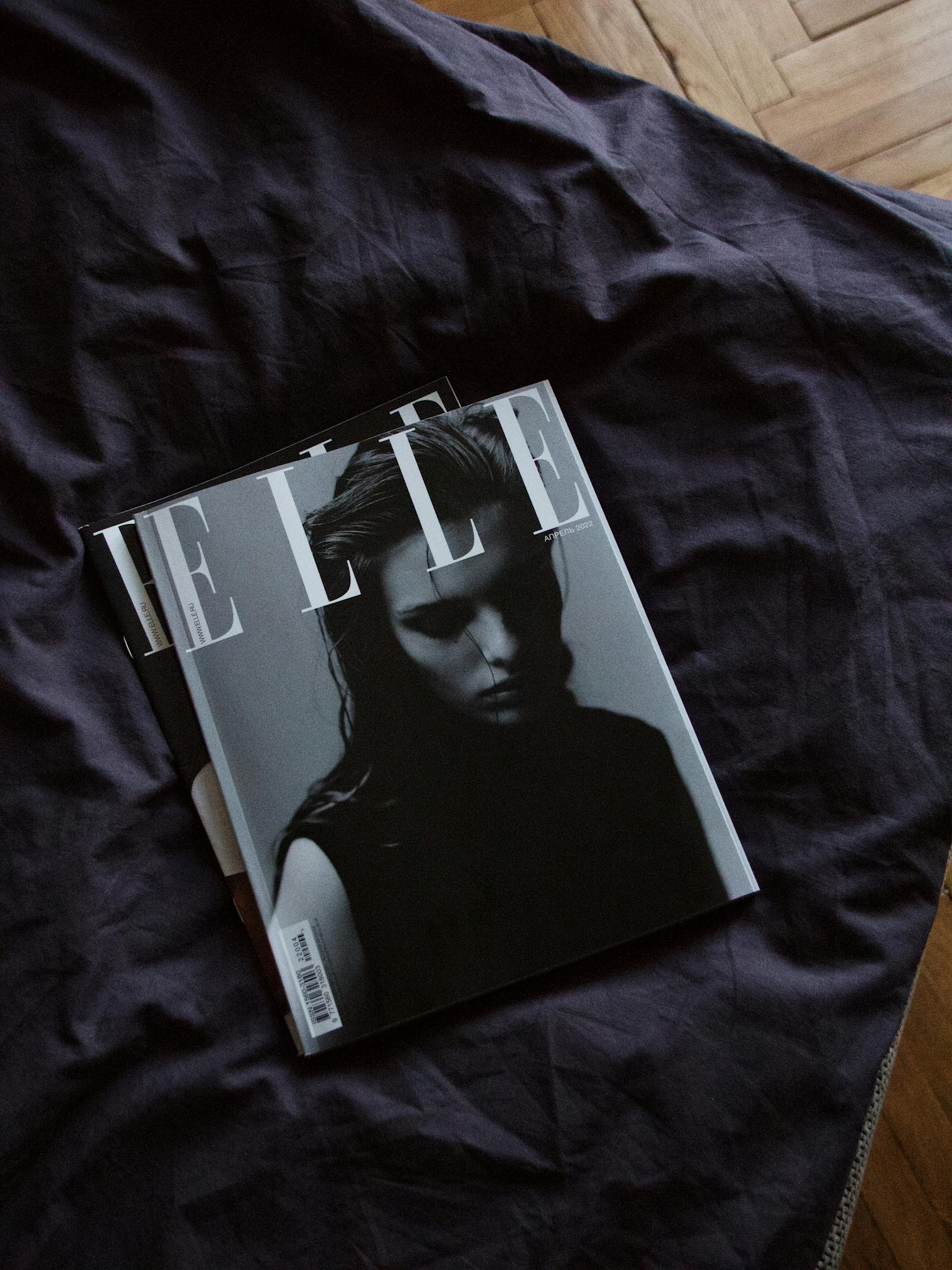 Elle fashion magazine on dark fabric with moody lighting.